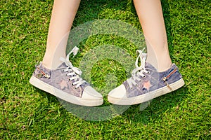 Youth sneakers on girl legs on grass