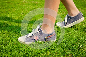 Youth sneakers on girl legs on grass