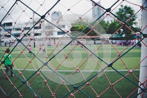 Youth soccer match tournament in a small soccer pitch blurred behind the net. Your football competition for youth sporting