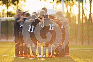 Youth sports players stand in a circle huddling together and motivating each other before the match