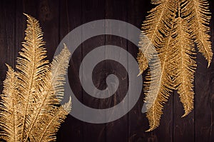 Youth stylish decoration for New Year party - decorative golden glittering branches on dark wood board, frame, top view.
