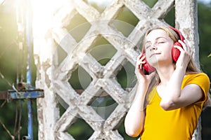 Youth and Teens Lifestyle. Dreaming Relaxing  Caucasian Teenager In Red Wireless Headphones Posing in Casual Outfit Against Grunge