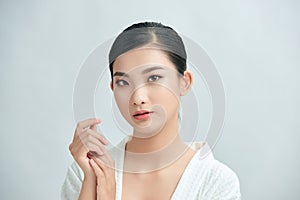 Youthful bright skin pretty Asian woman with hand touching face on white background for beauty concepts