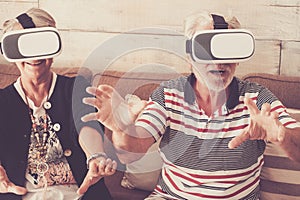 Youthful concept with old senior couple enojying goggled headset together in online modern games and virtual reality experience -