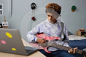 Youthful guy in hoodie looking at laptop screen during online lesson