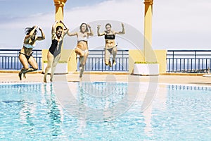 Youthful happy young people jumping together in the swimming pool enjoying the summer holiday vaction season - friends hace fun photo