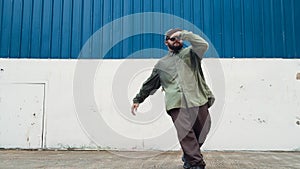 Youthful hipster dancing b-boy foot step at street with blue wall. Endeavor.