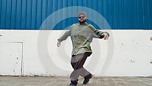 Youthful hipster dancing b-boy foot step at street with blue wall. Endeavor.