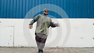 Youthful hipster dancing b-boy foot step at street with blue wall. Endeavor.