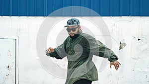 Youthful hipster dancing b-boy foot step at street with blue wall. Endeavor.