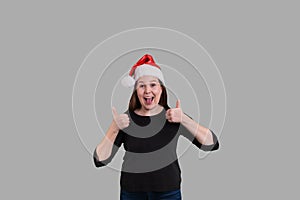 Youthful lady gesturing two thumbs up wearing a Christmas holiday Santa Claus hat