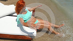 Youthful old woman in blue bikini having fun near the sea