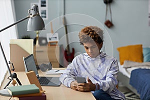 Youthful serious guy in casualwear texting in mobile phone