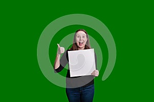 Youthful women giving a thumbs up holding a blank white board excited expression on green screen background