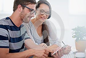 Youve done well on this mobi-site. two coworkers looking at a smartphone while sitting at a desk in an office.