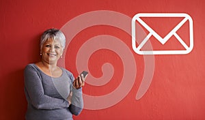 Youve got mail. a mature woman holding a mobile phone with a message icon beside her on the wall.