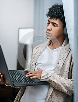 When youve officially watched everything on the internet. a young man using a laptop and headphones at home.