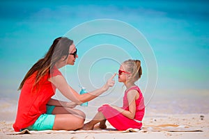 Ypung mother applying sun cream to daughter nose