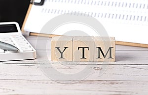 YTM word on a wooden block with clipboard and calculator