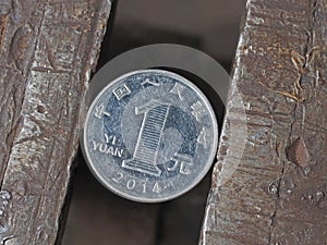 Yuan coin clamped in a metal vise. Currency under the onslaught, the concept of financial problems and crisis