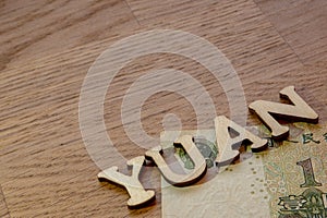 yuan word concept made of wooden letters on wooden background with Chinese flag