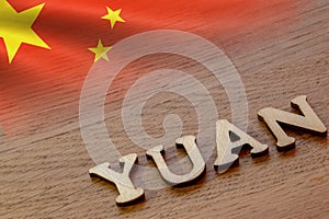 yuan word concept made of wooden letters on wooden background with Chinese flag