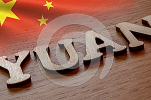 yuan word concept made of wooden letters on wooden background with Chinese flag