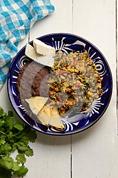 Yucatecan cuisine with our Huevo con Chaya. Scrambled eggs with indigenous chaya, succulent tomatoes, onion, refried beans, and