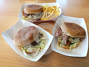 A yummy big lunch with 3 beef burger with french fries on white paper tray on the wood table photo