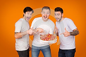 Yummy! Mates Pointing On Pizza Over Orange Background