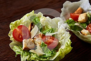 Yummy top view composition of fresh healthy salad served in lettuce leaves on wooden table.
