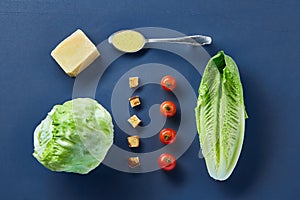 Yummy top view composition of fresh healthy salad ingredients on dark background.