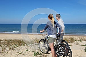 Yung couple biking on sandy dunes