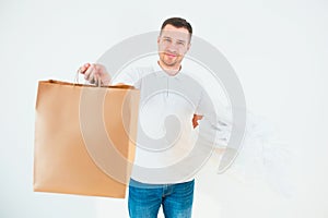 Yung man isolated over white background. Guy hold plastic bags in one hand and paper one in another. Recycling process