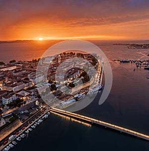 Zadar, Croatia - Aerial panoramic view of the old town of Zadar with colorful dramatic sunset sky, illuminated City Bridge