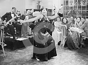 Zaftig woman performing a dance in front of a group of people in a restaurant