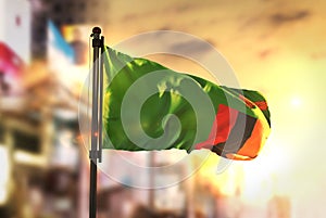 Zambia Flag Against City Blurred Background At Sunrise Backlight