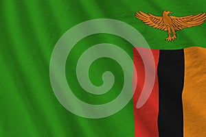 Zambia flag with big folds waving close up under the studio light indoors. The official symbols and colors in banner