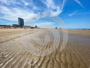 View on sand beach with umbrellas at dutch north sea in summer with blue sky and few cirrus clouds