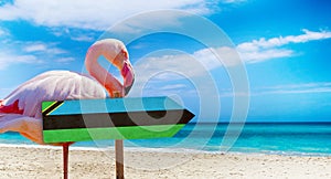 Zanzibar flag on wooden table sign on beach background with pink flamingo. There is beach and clear water of sea and blue sky in