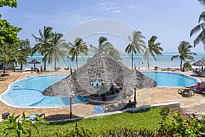 European tourists relaxing at the beach bar in the swimming pool at a tropical resort near the sea on the island of Zanzibar,