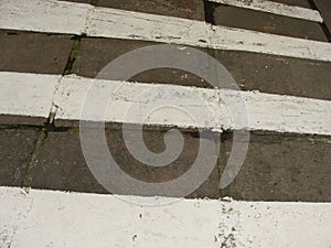 Zebra crossing. Asphalt background texture with some soft shades and spots.Road with black and white crosswalk