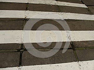 Zebra crossing. Asphalt background texture with some soft shades and spots.Road with black and white crosswalk