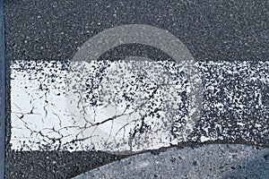 Zebra crossway with some faded on asphalt road close-up view