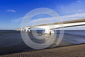 Zeeland Bridge - a long white bridge over a river illuminated by beautiful light, a beautiful blue sky with white clouds. Blue