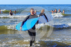 ZELENOGRADSK, KALININGRAD REGION, RUSSIA - JULY 29, 2017: Unknown surfers with surfboards standing in the blue water.