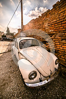 Zemun, Serbia - 17 February 2019 - Old rusted white Volkswagen Beetle parked next to orange brick wall