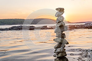 Zen balanced stones stacked on sea coast at sunset. Balance and equilibrium concept