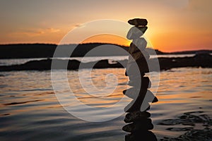 Zen balanced stones stacked on sea coast at sunset. Balance and equilibrium concept