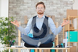 zen businessman doing yoga meditation on desk
